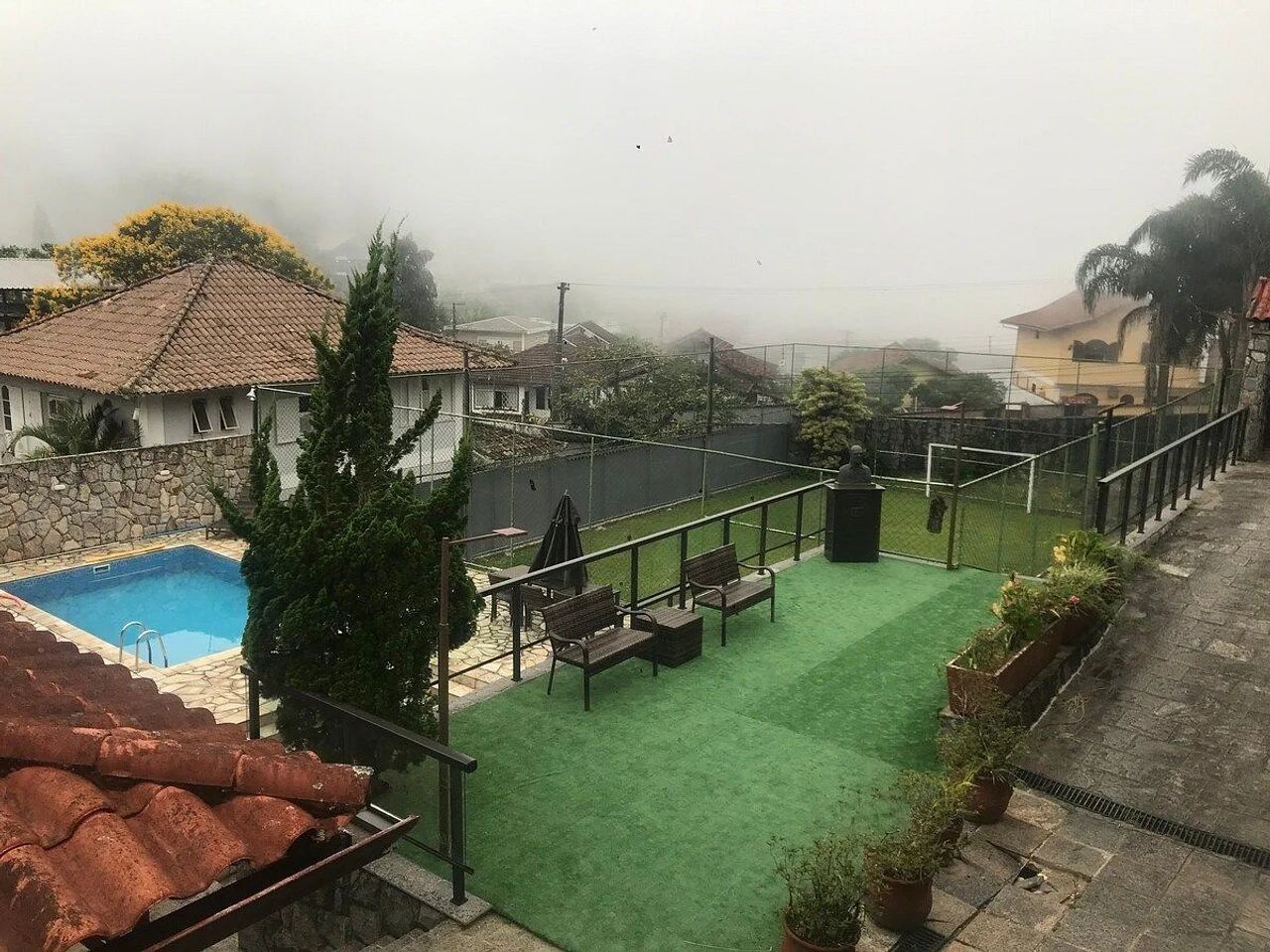 Un espace piscine aménagé sur le toit, avec une pelouse artificielle verdoyante, un mur en pierre et une vue dégagée sur le quartier environnant.