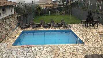 Une piscine rectangulaire bordée de carreaux de pierre et entourée d’un muret en pierre.