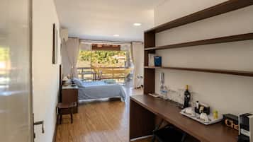 A hotel room with a bed, desk, chair, and a view of the outdoors.