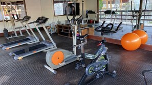 Un gimnasio con cintas de correr, elípticas y pelotas de ejercicio.