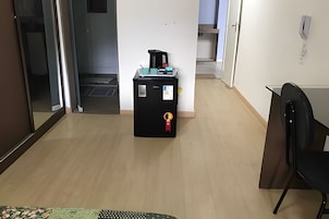 Habitación de hotel con distribución compacta, que incluye una cama, un escritorio pequeño y una zona de kitchenette.