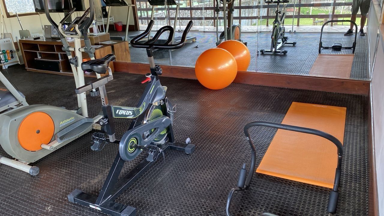 Een fitnessruimte met cardioapparatuur, trainingsballen en een spiegel.