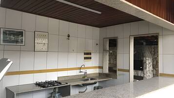 A kitchen with a granite countertop, a gas stove, and a stone backsplash.