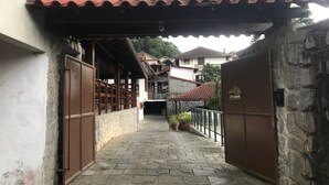 Un carrer estret amb teulada de rajola, parets de pedra i portes de fusta.
