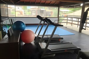 A gym with exercise equipment, including a treadmill and exercise balls, with a view of buildings outside.