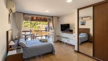 Een slaapkamer met een bed, nachtkastje, televisie en een balkon met hangmat.