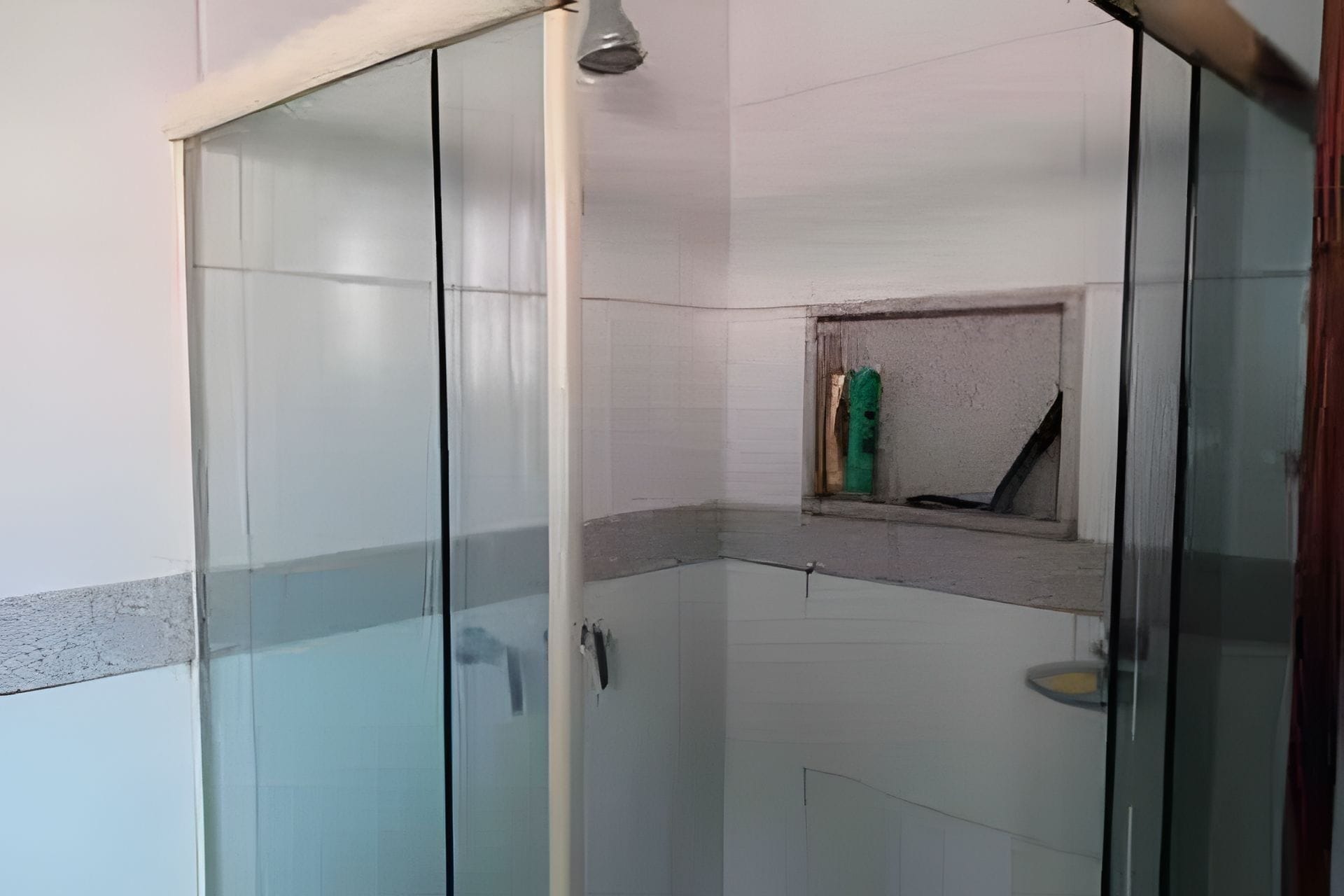 A glass-enclosed shower area with a small shelf and a towel rack.