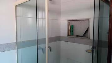 A glass-enclosed shower area with a small shelf and a towel rack.