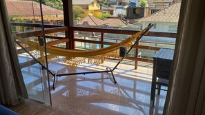 A hammock on a balcony with a view of buildings.