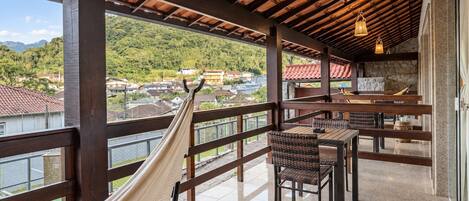 Ein Balkon mit einer Hängematte, Holzmöbeln und Blick auf eine Wohngegend.
