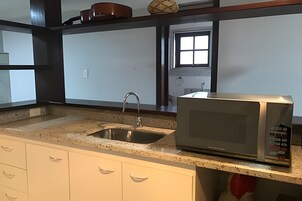 Una cocina con un lavamanos de acero inoxidable, un microondas y una ventana con vistas al exterior.