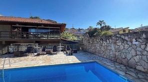 Un área de piscina con muros de piedra y sillones de descanso.