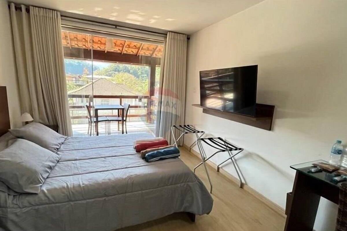 Habitación de hotel con cama, televisor montado en la pared, escritorio con silla y vista al exterior por una ventana.