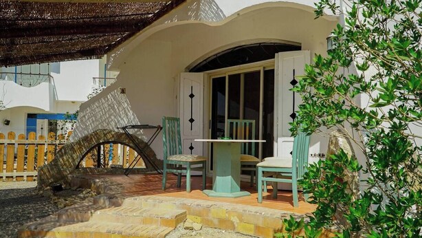 A covered outdoor seating area with a stone bench, a table, and chairs. - WHITE VILLA No. 8
 (Hurghada)
