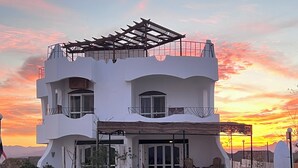 A two-story white building with a covered patio and a white picket fence. - WHITE VILLA No. 8
 (Hurghada)