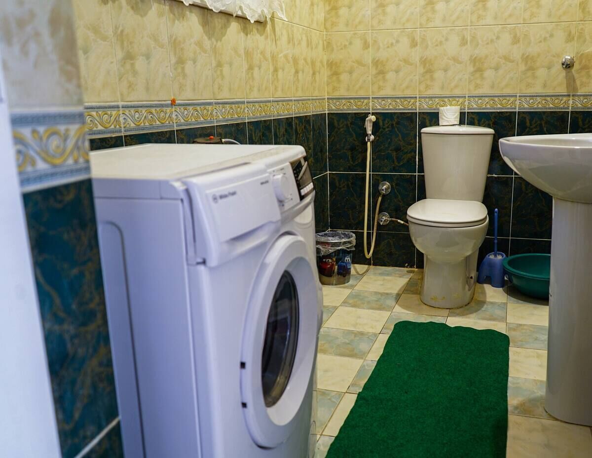 Een kleine badkamer met een wasmachine, toilet en wastafel.