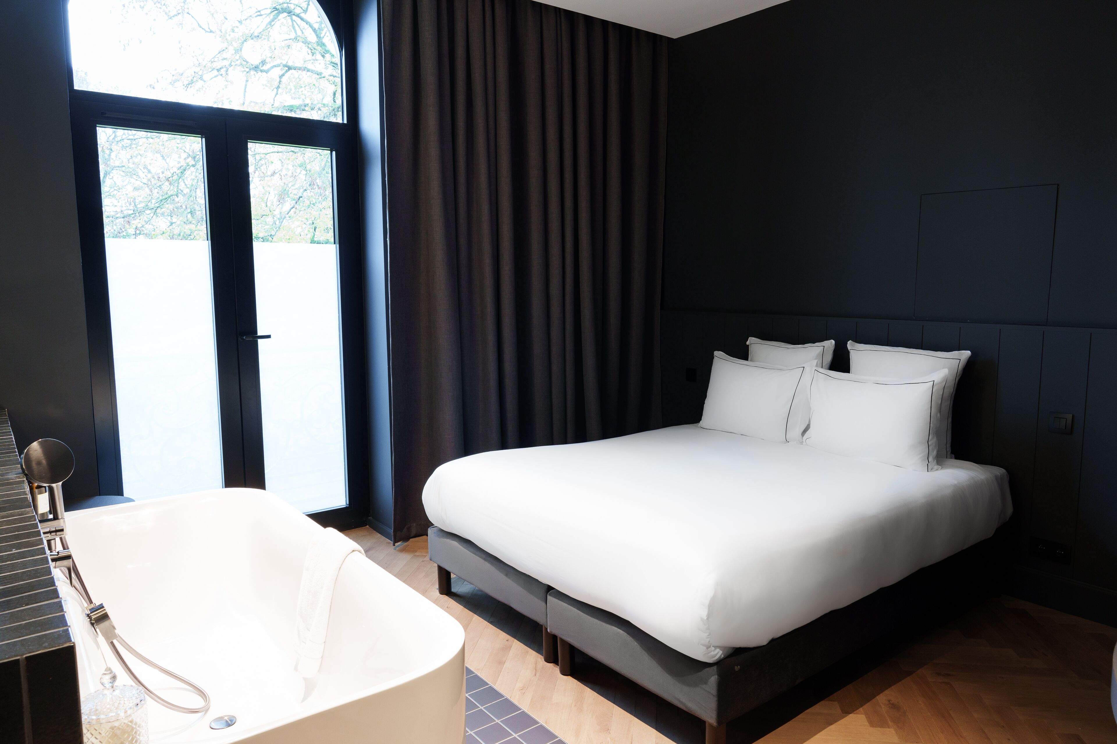 Un dormitorio moderno con una cama grande, una bañera y vistas al exterior.