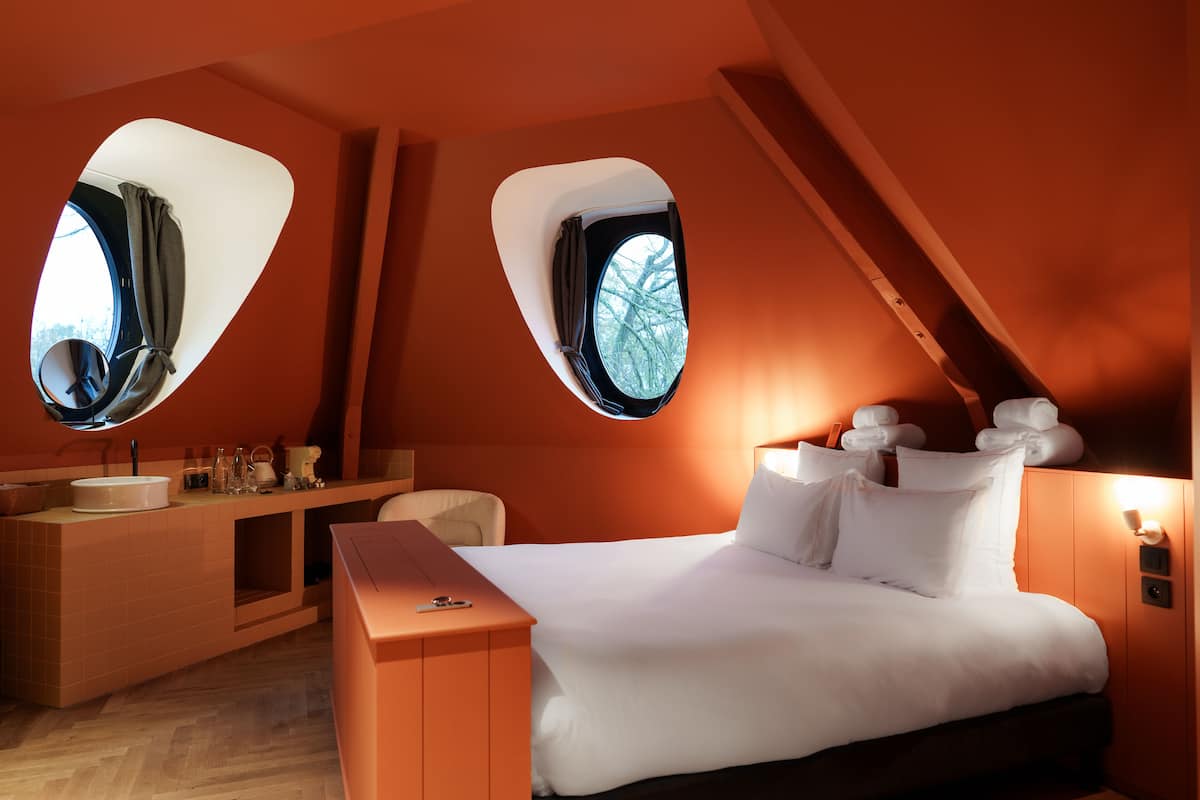 Un dormitorio moderno con una cama grande, un tocador con espejo y dos ventanas con cortinas.