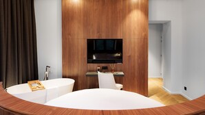 Un baño moderno con tocador de madera, una bañera y un televisor de pantalla plana montado sobre el tocador.
