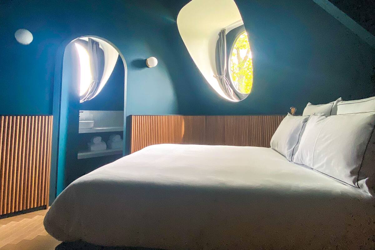 Un dormitorio con una cama grande, dos ventanas y un techo inclinado.