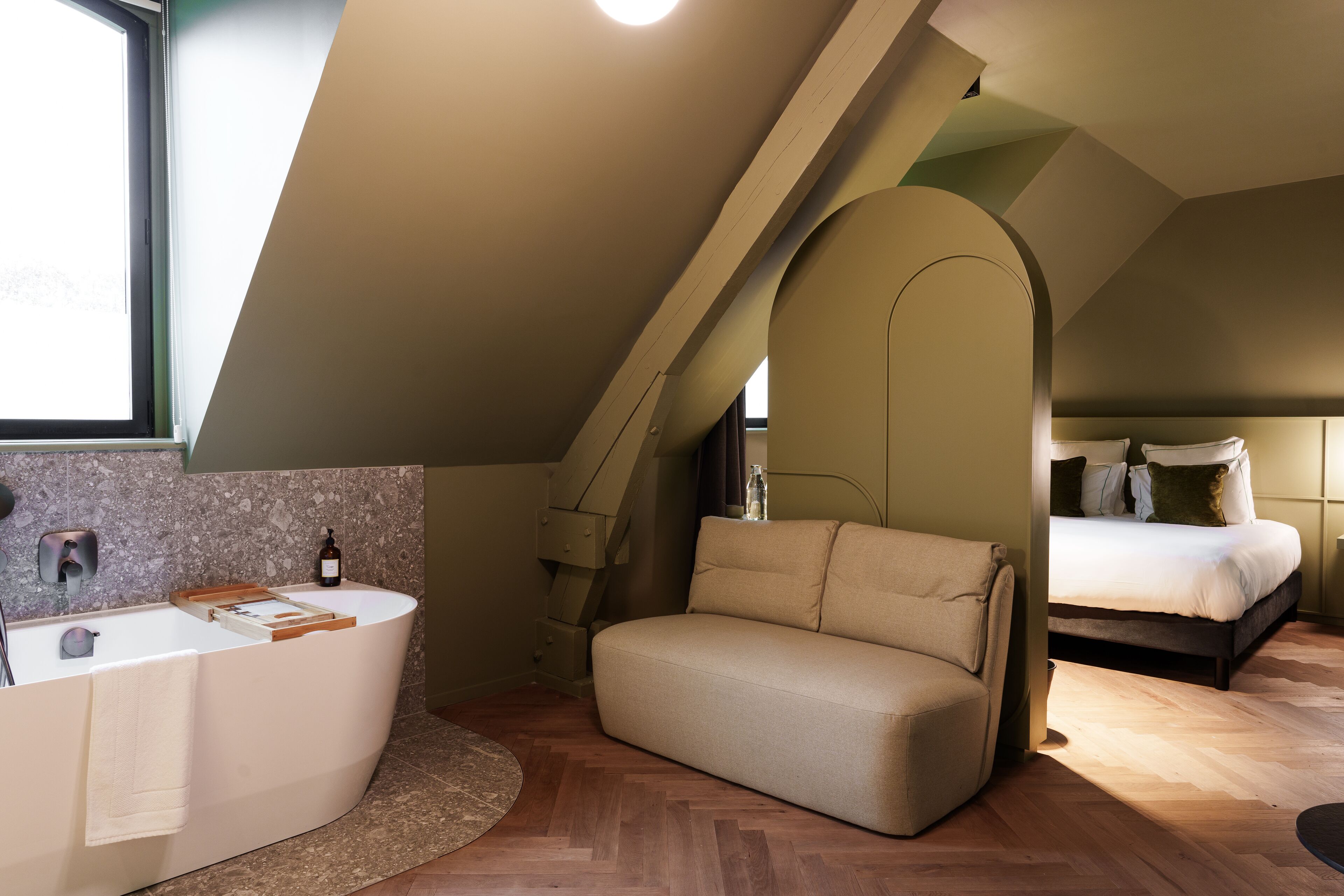 Una camera da letto moderna con un letto grande, un divano e una vasca da bagno.