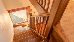 Una escalera de madera con vista a un muro de ladrillo y una ventana.