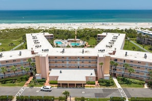 A hotel with a pool, beach view, and multiple balconies.