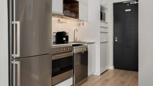 Een moderne keuken met roestvrijstalen apparatuur, een zwarte deur en witte kasten.