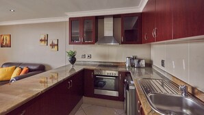 A modern kitchen with a Bosch oven, a sink, and a countertop. There is a dining area with a leather couch and a vase of flowers. - SEA-VIEW  APARTMENT - POINT WATERFRONT
near to beaches , harbour and restaurants (Durban)