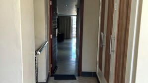 A hallway with tiled flooring, a metal handrail, and wooden doors. - SEA-VIEW  APARTMENT - POINT WATERFRONT
near to beaches , harbour and restaurants (Durban)