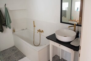 A bathroom with a bathtub, a sink, and a mirror. - theFritsch-Weinbauernhaus in the countryside (Klein-Reinprechtsdorf)
