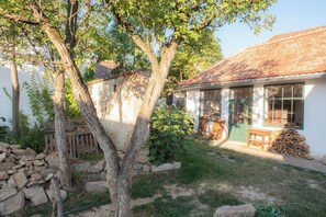 A rustic building with a tiled roof, a stone wall, and a tree in the foreground. - theFritsch-Weinbauernhaus in the countryside (Klein-Reinprechtsdorf)