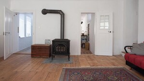 Een woonkamer met een houtkachel, een rode bank en een kamerbreed tapijt.