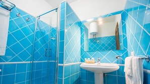 A bathroom with blue tiles, a glass shower enclosure, a sink, and a mirror. - Relaxing Le Residenze del Maria Rosaria No2227h (Orosei)