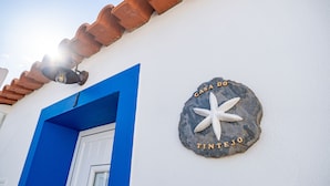 A building with a blue door and a sign that reads "Casa do Pintanejo" on a stone wall.