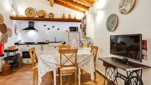 A kitchen with a white brick backsplash, wooden ceiling beams, and a dining area with a table and chairs.