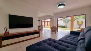 A modern living room with a large flat-screen TV, a dark sofa, and a wooden entertainment unit.