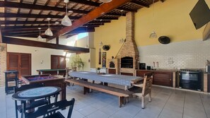 Un comedor interior con un horno de ladrillo, mesas de madera y un mantel a cuadros.