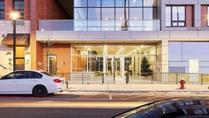 A modern building with a glass entrance, a fire hydrant, and a parked white car.