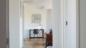 Une pièce moderne et minimaliste, dotée d’un plancher en bois, d’un bureau avec une chaise et d’une œuvre d’art abstraite accrochée au mur.
