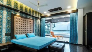 Een moderne slaapkamer met een groot bed, een gestoffeerd hoofdeinde, een bankje en uitzicht op de omgeving.