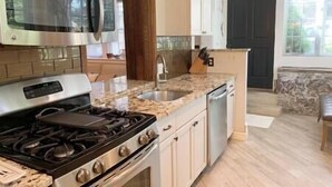 A kitchen with a gas stove, stainless steel appliances, a granite countertop, and a sink. - C&J Signature Stays Historic renovated apartment (Morristown)
