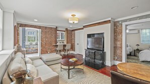 A modern living room with a fireplace, a sofa set, and a dining table. - C&J Signature Stays Historic renovated apartment (Morristown)