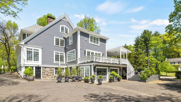 A large, two-story house with a balcony, multiple windows, and a driveway with potted plants. - C&J Signature Stays Historic renovated apartment (Morristown)