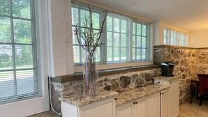 A kitchen with stone countertops, white cabinets, and large windows. - C&J Signature Stays Historic renovated apartment (Morristown)