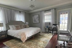 A bedroom with a large bed, a desk, and a chair.