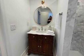 A bathroom with a round mirror, a white sink, and dark wooden cabinets.