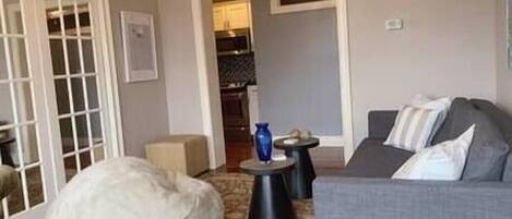 Un salon avec un canapé gris, un fauteuil en forme de poire blanc et une petite table ronde sur laquelle se trouve un vase bleu.