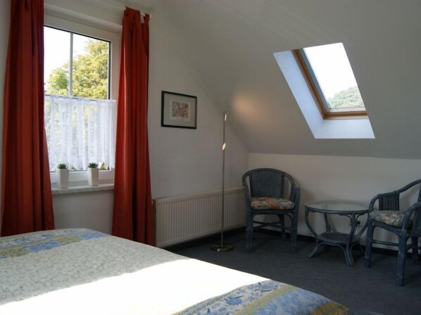 A bedroom with a bed, two chairs, a window with curtains, a radiator, and a skylight. - Apartment Bredi by Interhome (Zinnowitz)