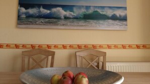 Ein Essbereich mit Tisch, Stühlen und einer Schüssel Äpfel.